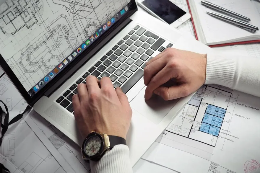 Tangan sedang mengerjakan data dan catatan melalui laptop